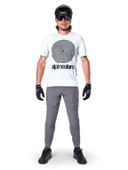 Alpinestars A-Dura Pants, MTB-fietsbroek, donkergrijs, gedragen met een wit grafisch t-shirt, zwarte helm en handschoenen, met een duurzaam 2-way stretch-ontwerp en regular fit voor mountainbiken