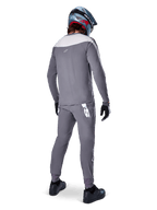 Alpinestars A-Supra Race Pants, Dark Gray, Mountain bike rider from behind wearing full racing kit, gray long-sleeved jersey, dark gray pants with white MX-inspired logo on back yoke, gray and blue helmet, black shoes, designed for MTB performance