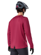 Alpinestars A-Dura Thermal Jersey, MTB-shirt met lange mouwen, bordeauxrood, achteraanzicht op model met een grijze MTB-helm en zwarte handschoenen, voorzien van een verlengde achterkant en kleine logo-details, ontworpen voor trailrijden in koud weer.