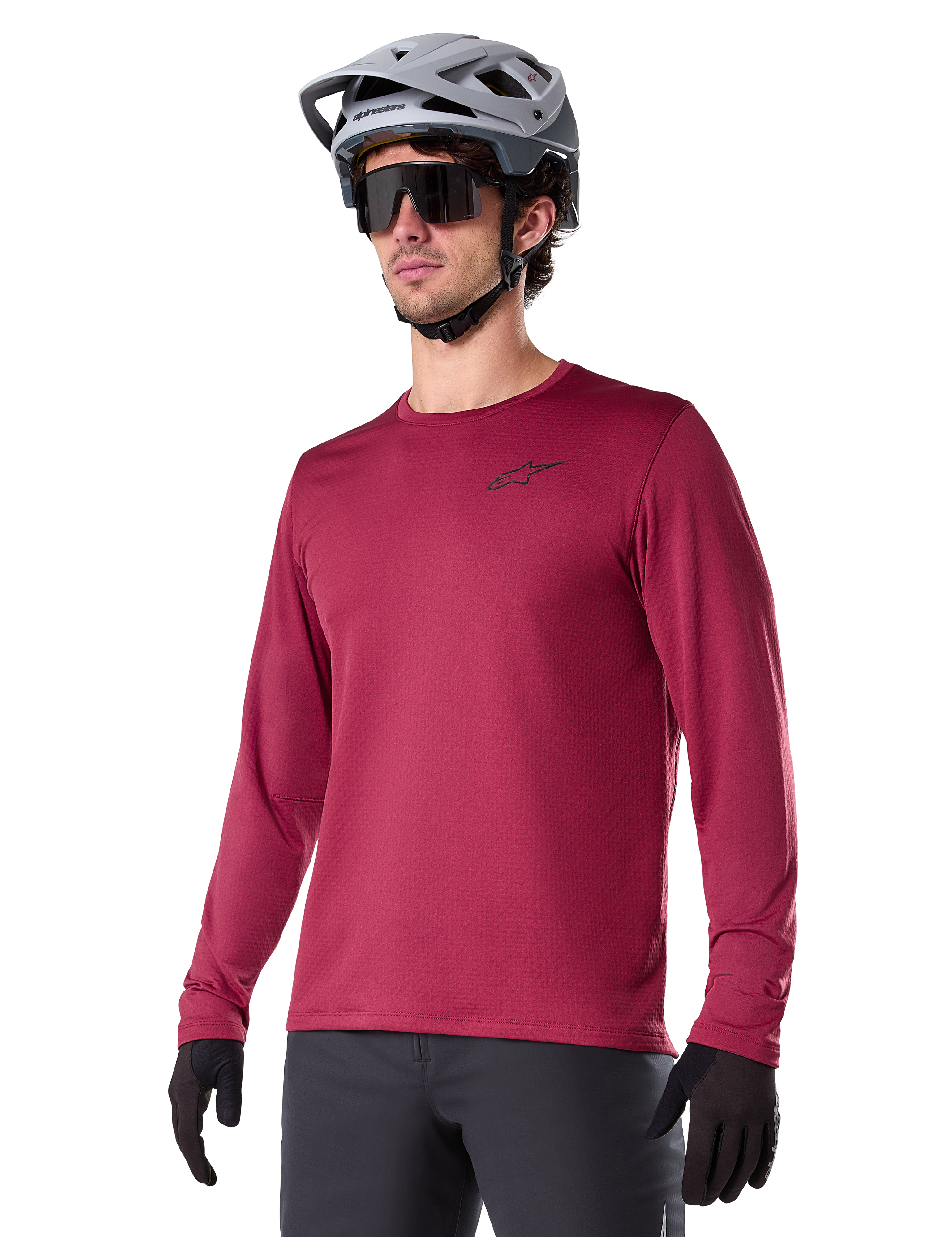 Alpinestars A-Dura Thermal Jersey, mountainbike-jersey met lange mouwen, bordeauxrood, voorzien van een geïsoleerde fleecevoering en klein zwart logo op de borst, gedragen met een grijze helm, zwarte zonnebril en zwarte handschoenen, ontworpen voor fietsen in koud weer