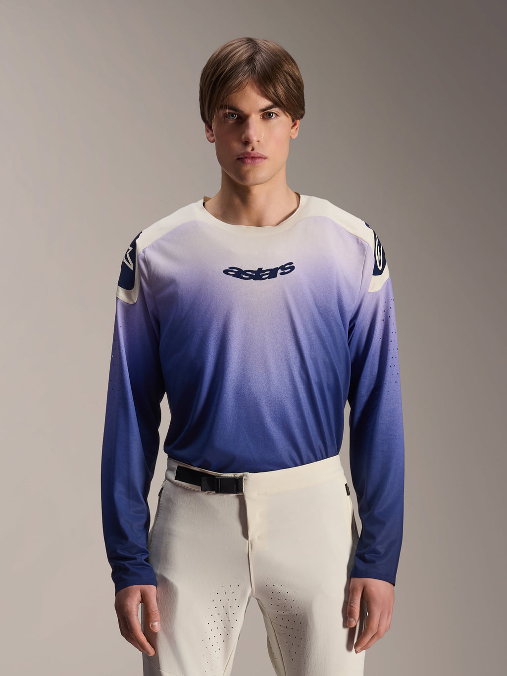 Alpinestars A-Aria Polartec Maker Elite jersey met lange mouwen, MTB-shirt, Baja Blue met een kleurverloop van wit naar blauw, gedragen door een model met een witte broek, donkerblauw logo op de borst en laserperforaties op de mouwen, technische mountainbikekleding