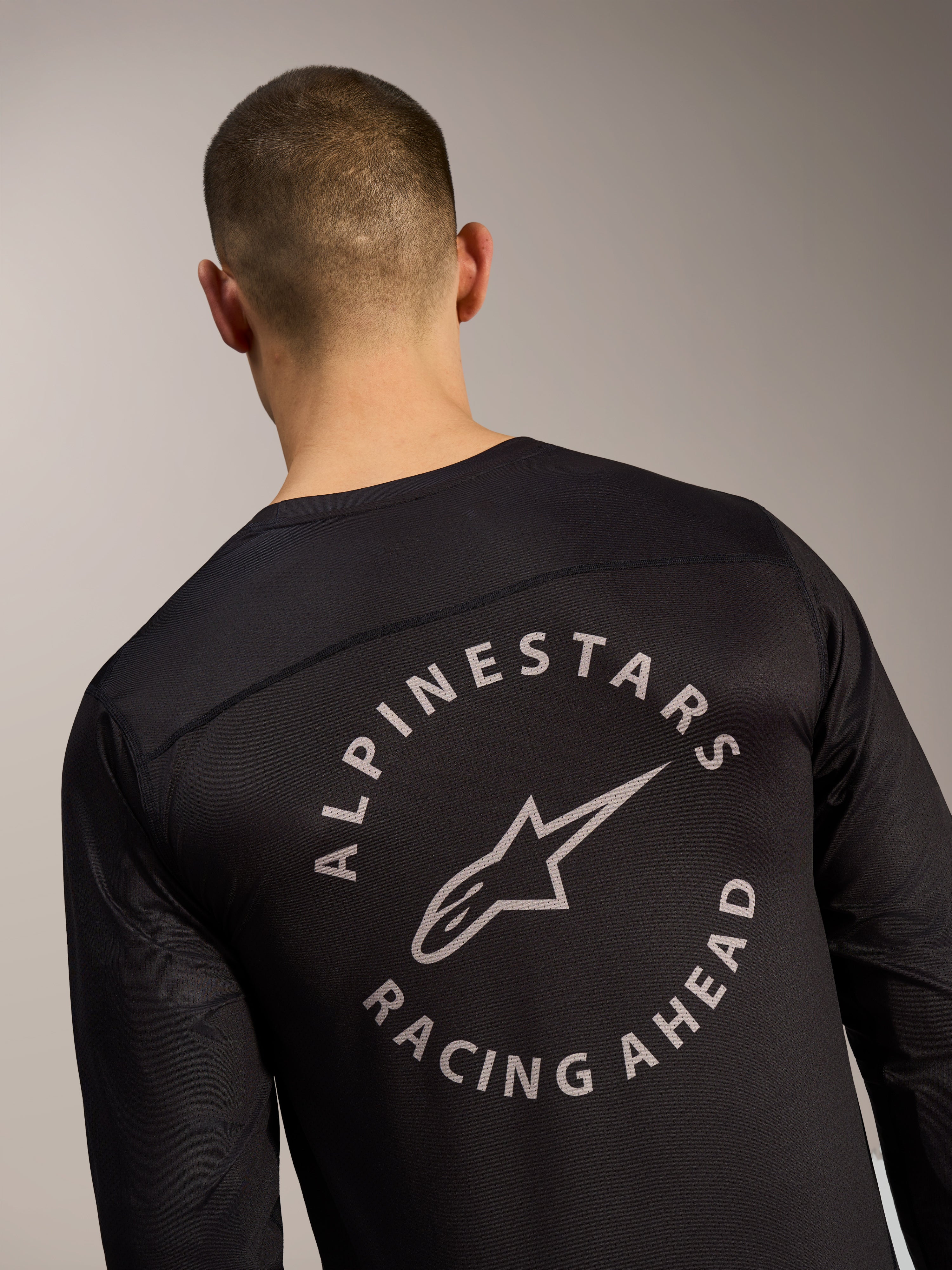 Zwarte A-Dura Air jersey met lange mouwen, rugdetail met cirkelvormig Alpinestars Racing Ahead-logo op mesh-stof.