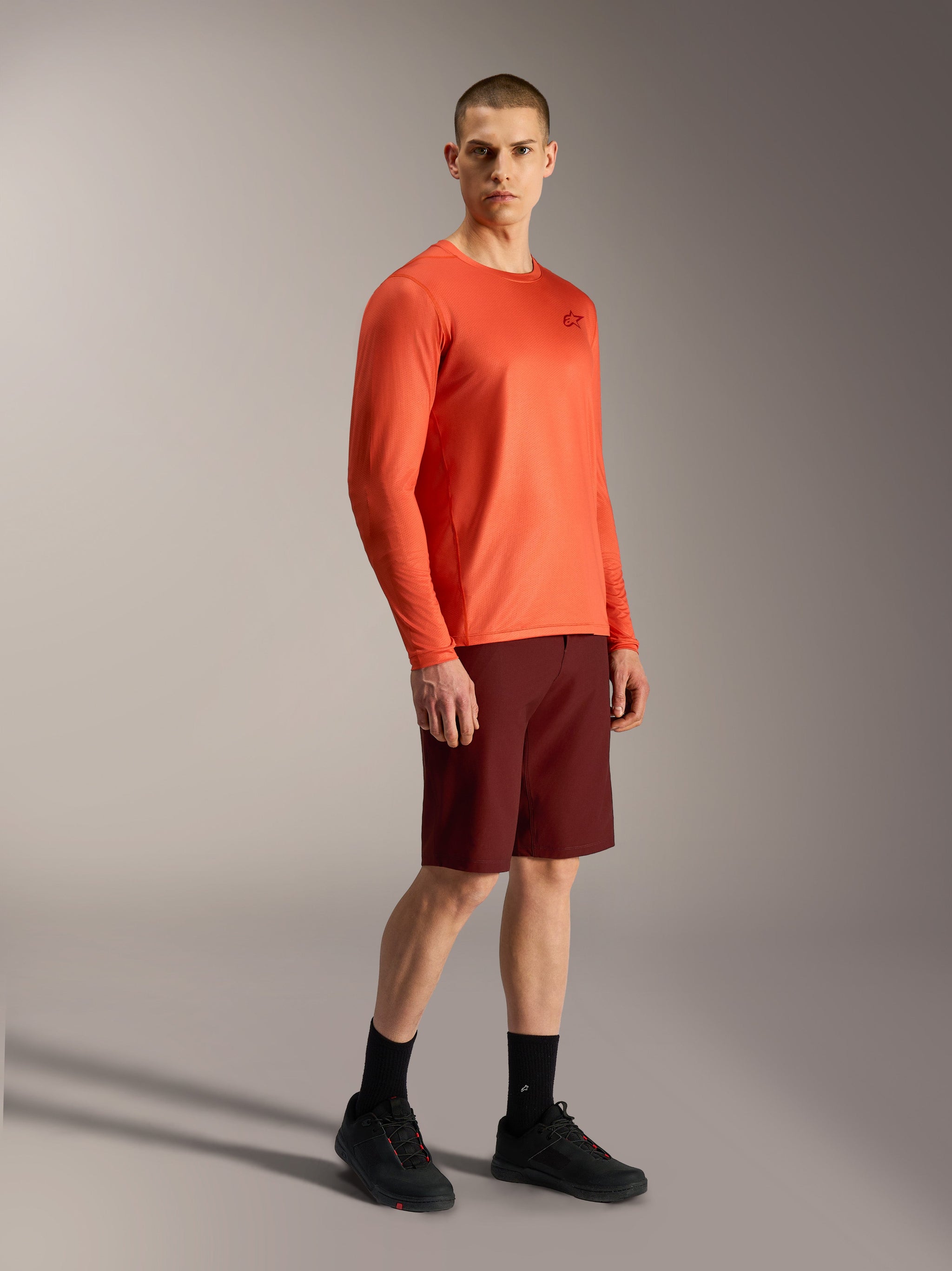 Alpinestars A-Dura Air oranje jersey met lange mouwen en bordeauxrode A-Dura Ride shorts, professionele MTB-uitrusting.