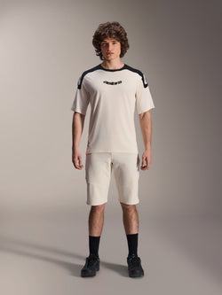 Alpinestars A-Aria Elite Shorts, mountainbike shorts, ecru, gedragen met bijpassend shirt met korte mouwen met zwarte schouderpanelen en logo, casual sportieve look met perforaties aan de voorzijde, performance MTB-kleding