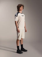 Mannelijk model in Alpinestars A-Aria Elite Shorts in Ecru, technische mountainbikeshorts met lasergesneden ventilatie, gecombineerd met een bijpassend crème en zwart fietsshirt met korte mouwen en zwarte schoenen, professionele wielerkleding.
