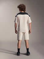 Alpinestars A-Aria Elite shorts en A-Aria Polartec Elite SS jersey, ecru met zwarte schouderpanelen, achteraanzicht van een model in mountainbike-performancekleding, gestyled met zwarte sokken en schoenen