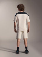 Alpinestars A-Aria Polartec Elite Jersey met korte mouwen, MTB-fietsshirt, ecru met zwarte schouderpanelen, achteraanzicht getoond met bijpassende short en zwarte sokken, prestatiegerichte pasvorm met een verlengde achterkant voor off-road rijden.
