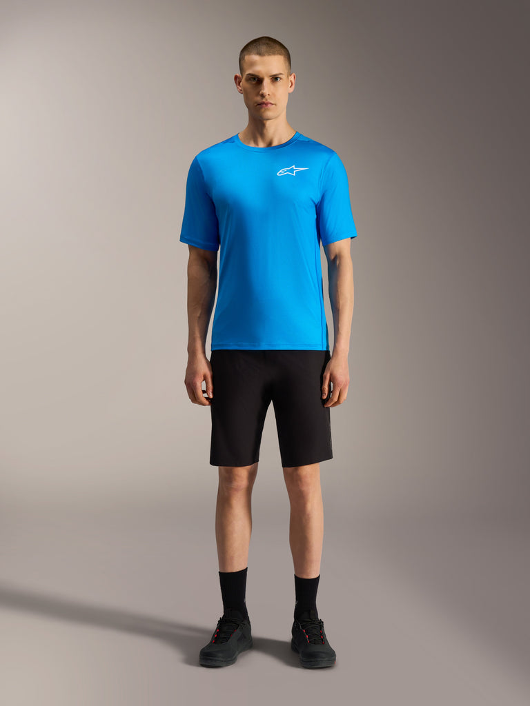 Alpinestars A-Dura Ride-short in zwart met een felblauwe jersey, technische mountainbikekleding op een model.
