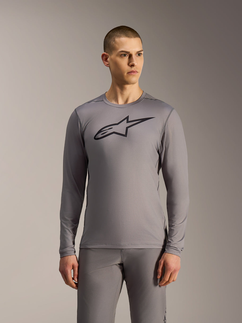Grijze Alpinestars A-Dura Ride MTB-jersey met lange mouwen, zwart borstlogo en ademende mesh-constructie.