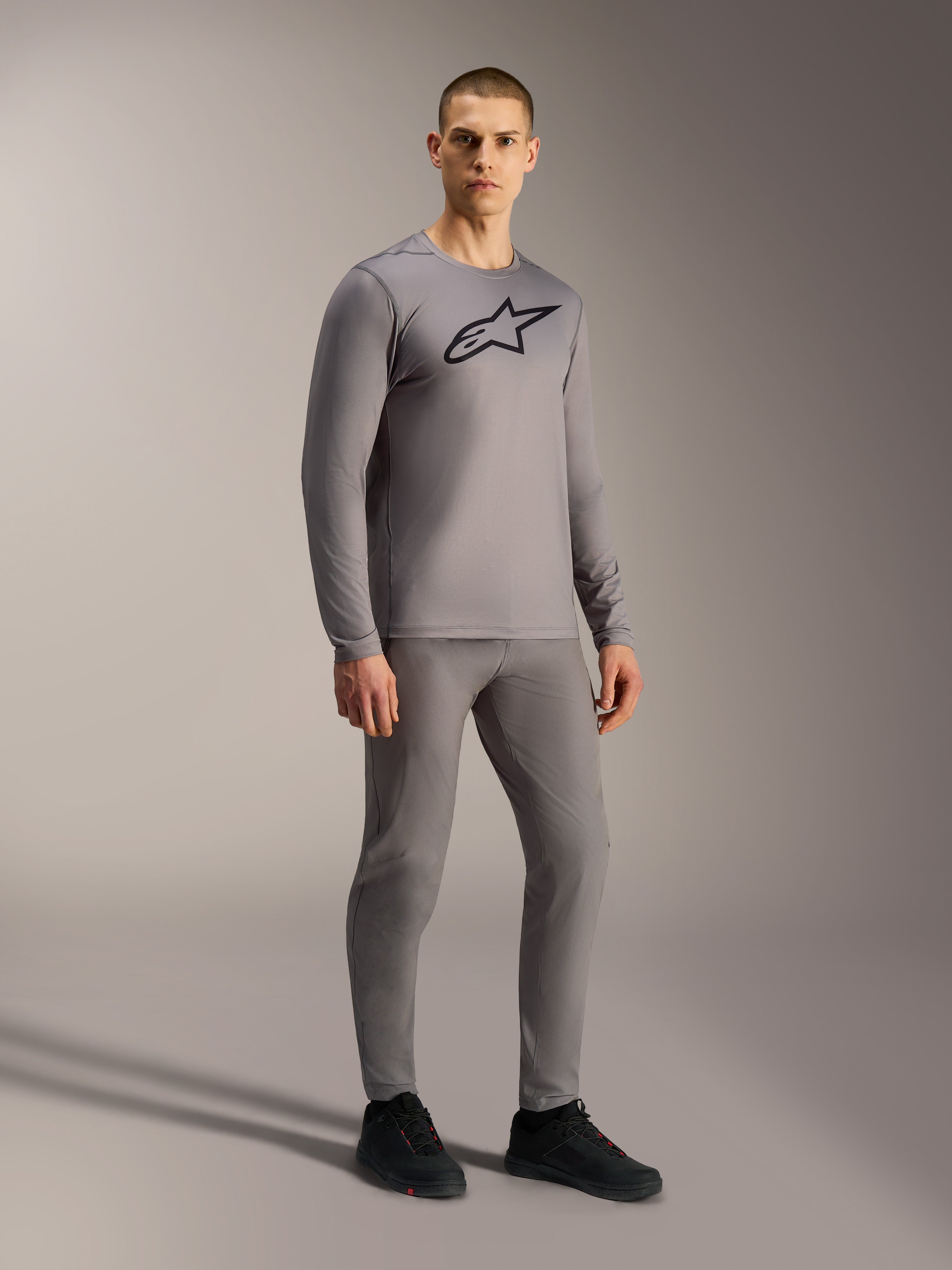 Grijze A-Dura Ride jersey met lange mouwen en zwart borstlogo, op een model voor een complete mountainbike-look.