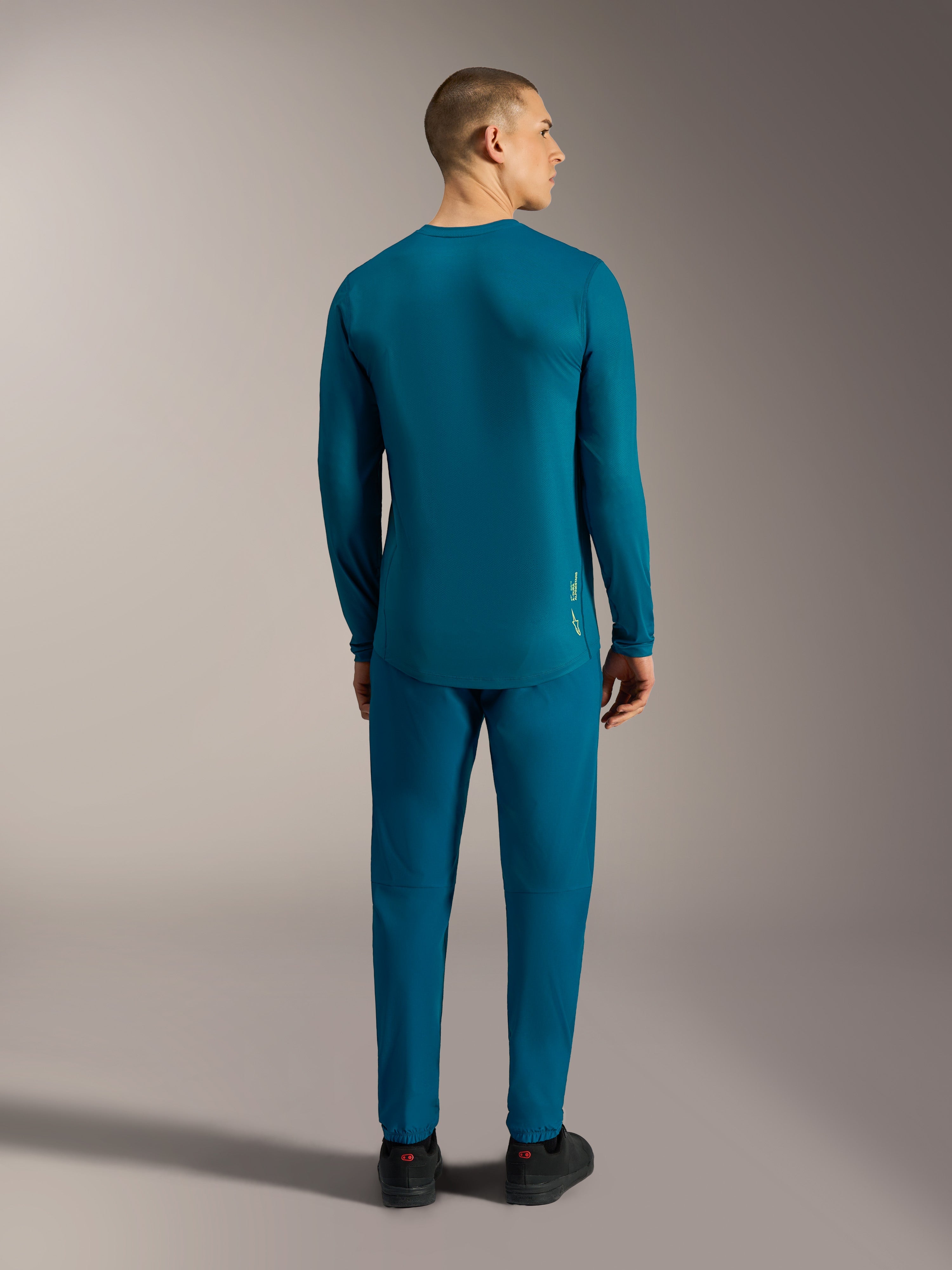 Blauwgroene A-Dura Ride Jersey met lange mouwen, achteraanzicht met een verlengde zoom voor mountainbiken.