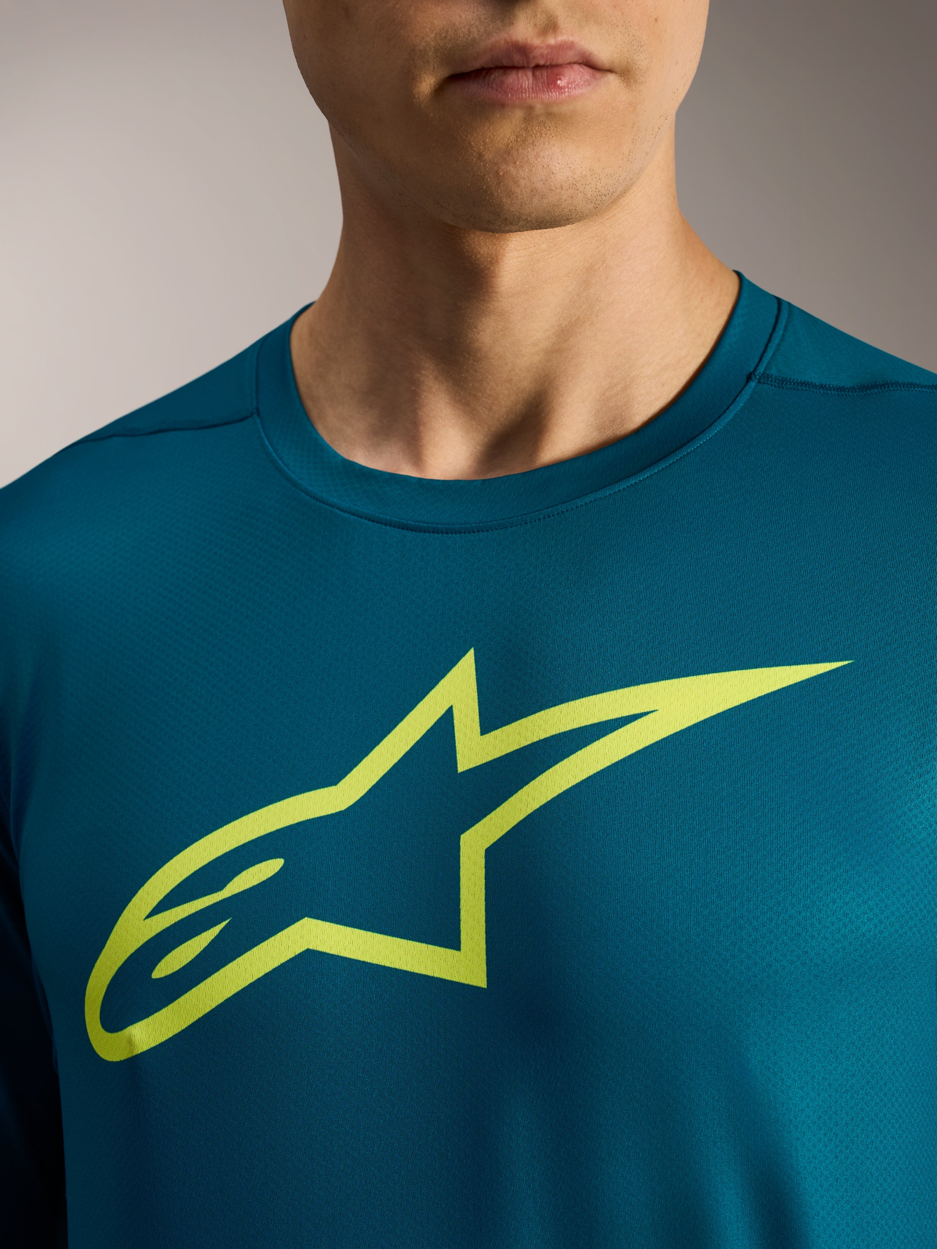 Blauwgroene A-Dura Ride MTB-trui met lange mouwen en een opvallend limegroen Astars-logo op de borst.
