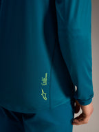 Blauwgroene A-Dura Ride jersey met lange mouwen en limoengroene Alpinestars-branding op de getextureerde achterzoom.