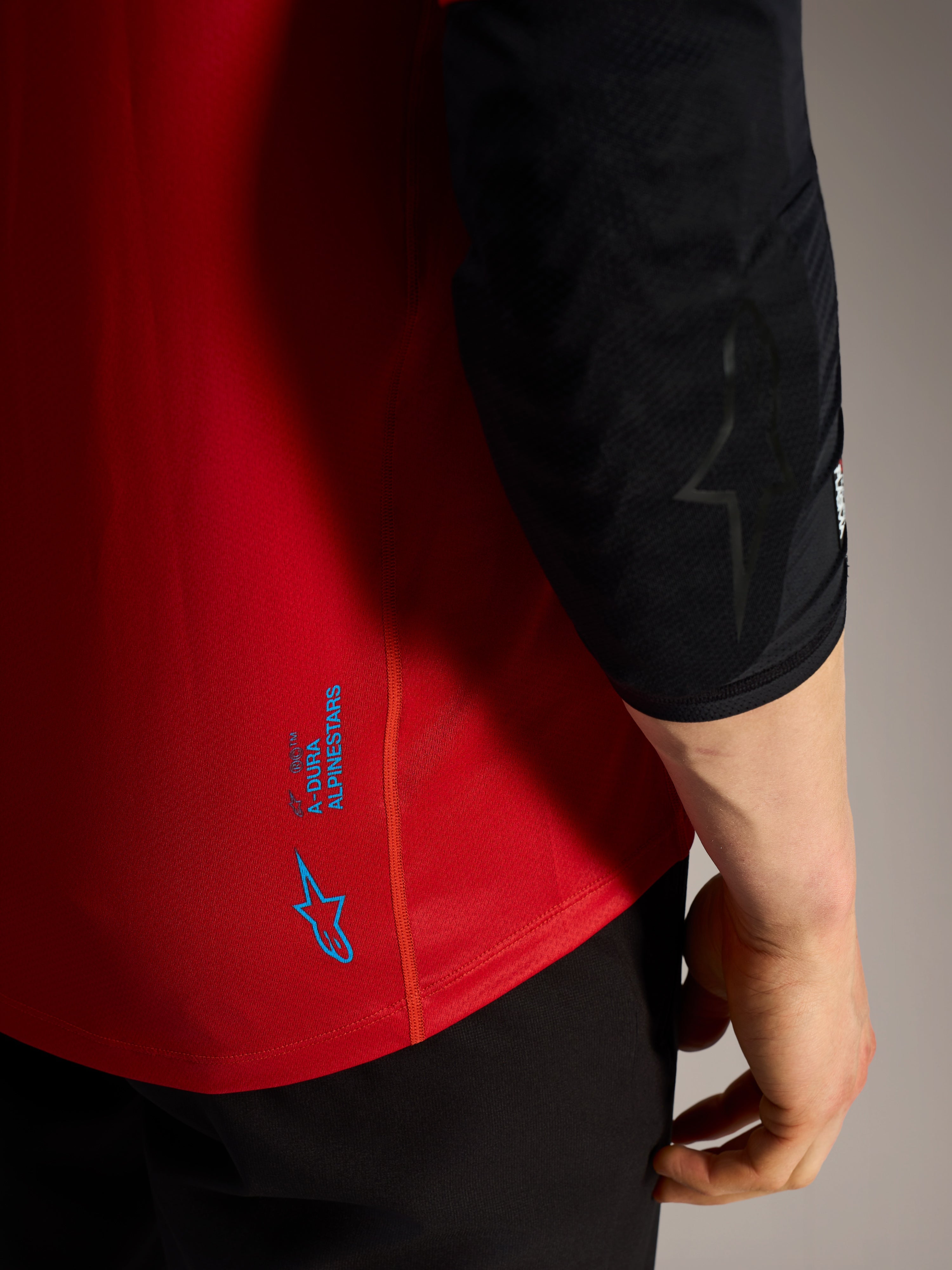 Rode A-Dura Ride MTB-trui met korte mouwen, voorzien van blauwe Alpinestars logo's en technische stretchstof.
