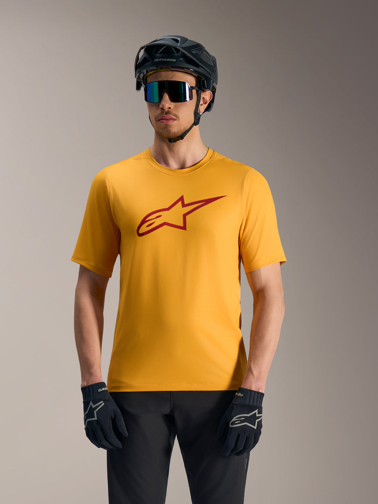 Oranje A-Dura Ride fietsshirt met rood Astars-logo, korte mouwen, gestyled met mountainbikehelm en handschoenen.