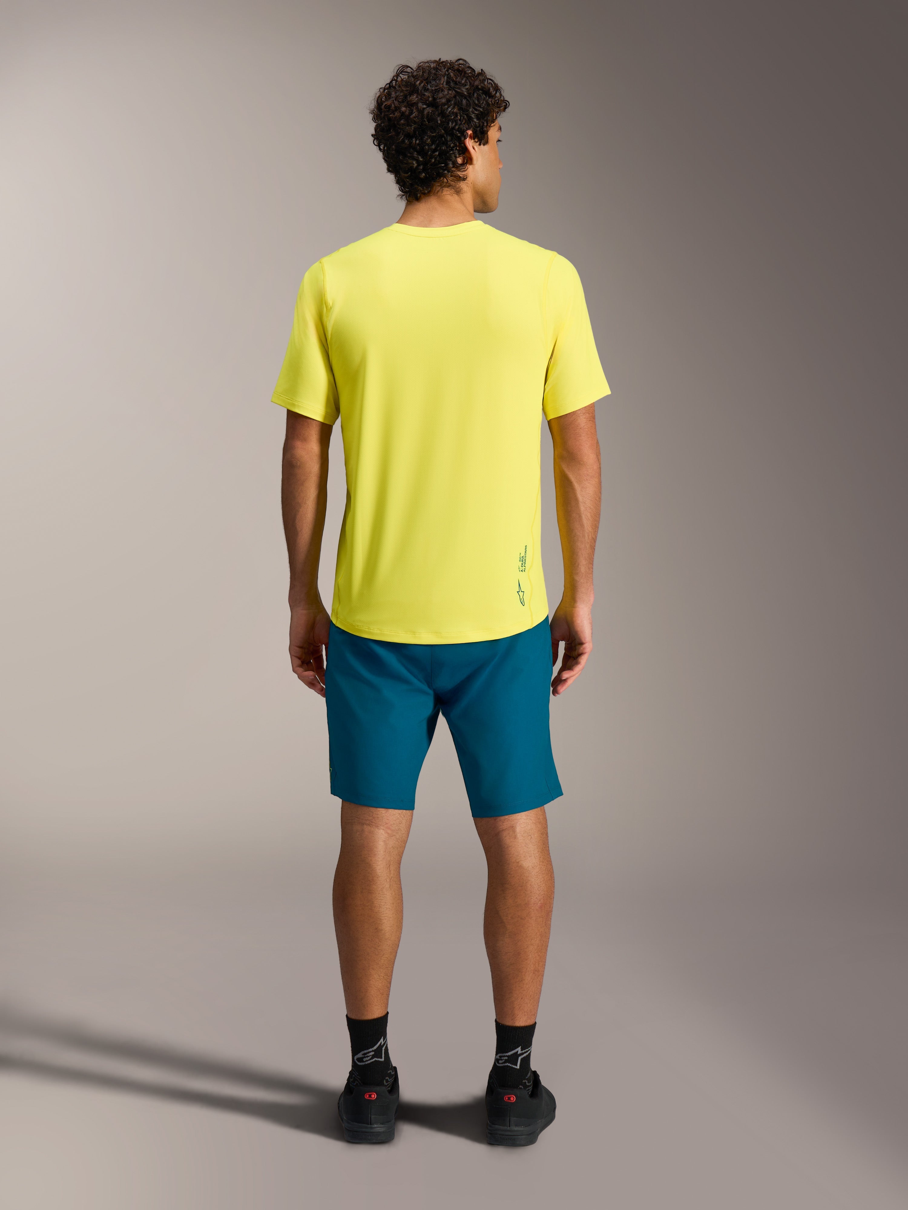 Gele A-Dura Ride SS Jersey en blauwgroene shorts, achteraanzicht van MTB-prestatiekleding.