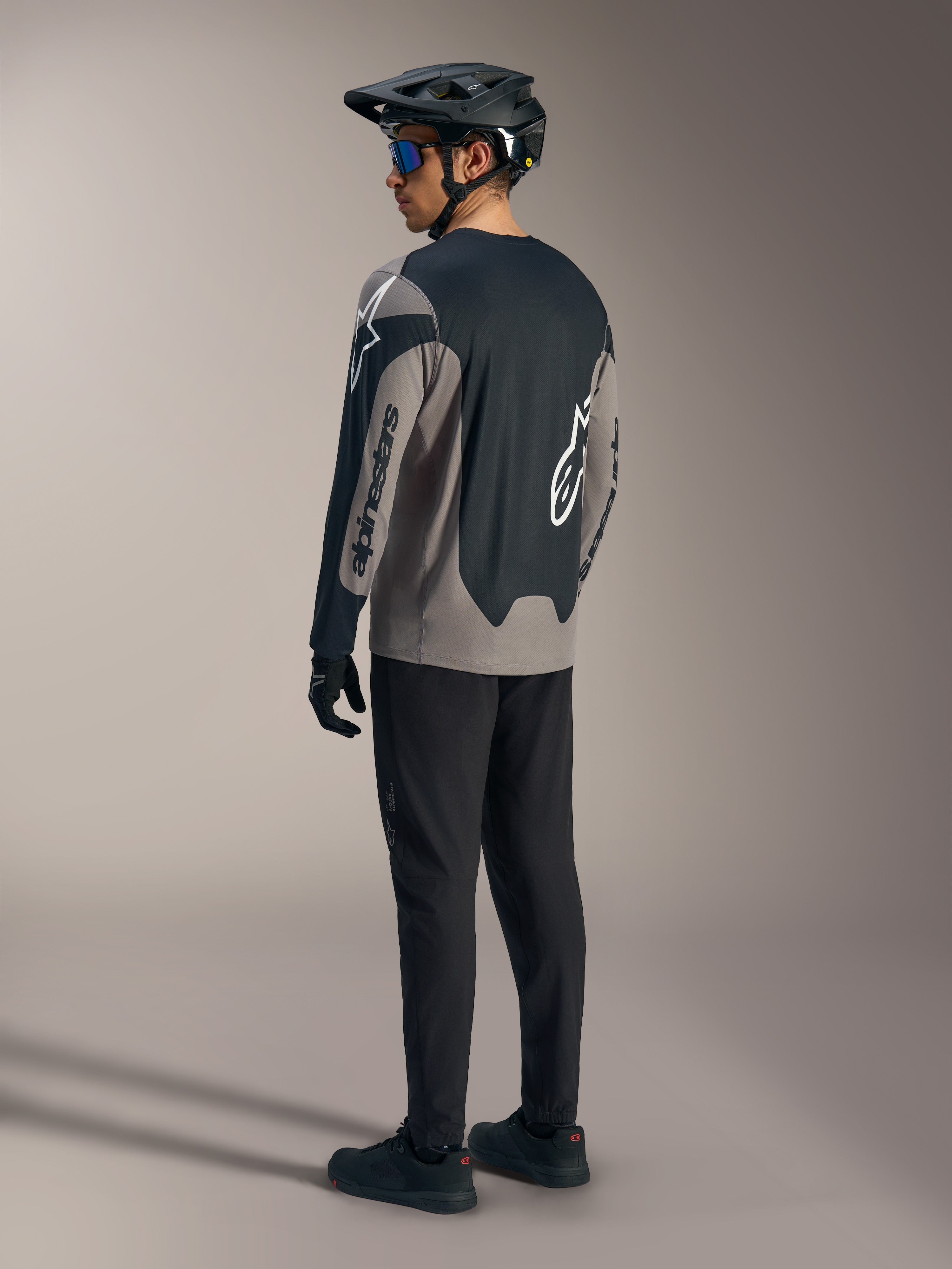 Grijze en zwarte A-Dura Race Jersey met lange mouwen en Alpinestars-branding, van achteren gezien in een MTB-kit.
