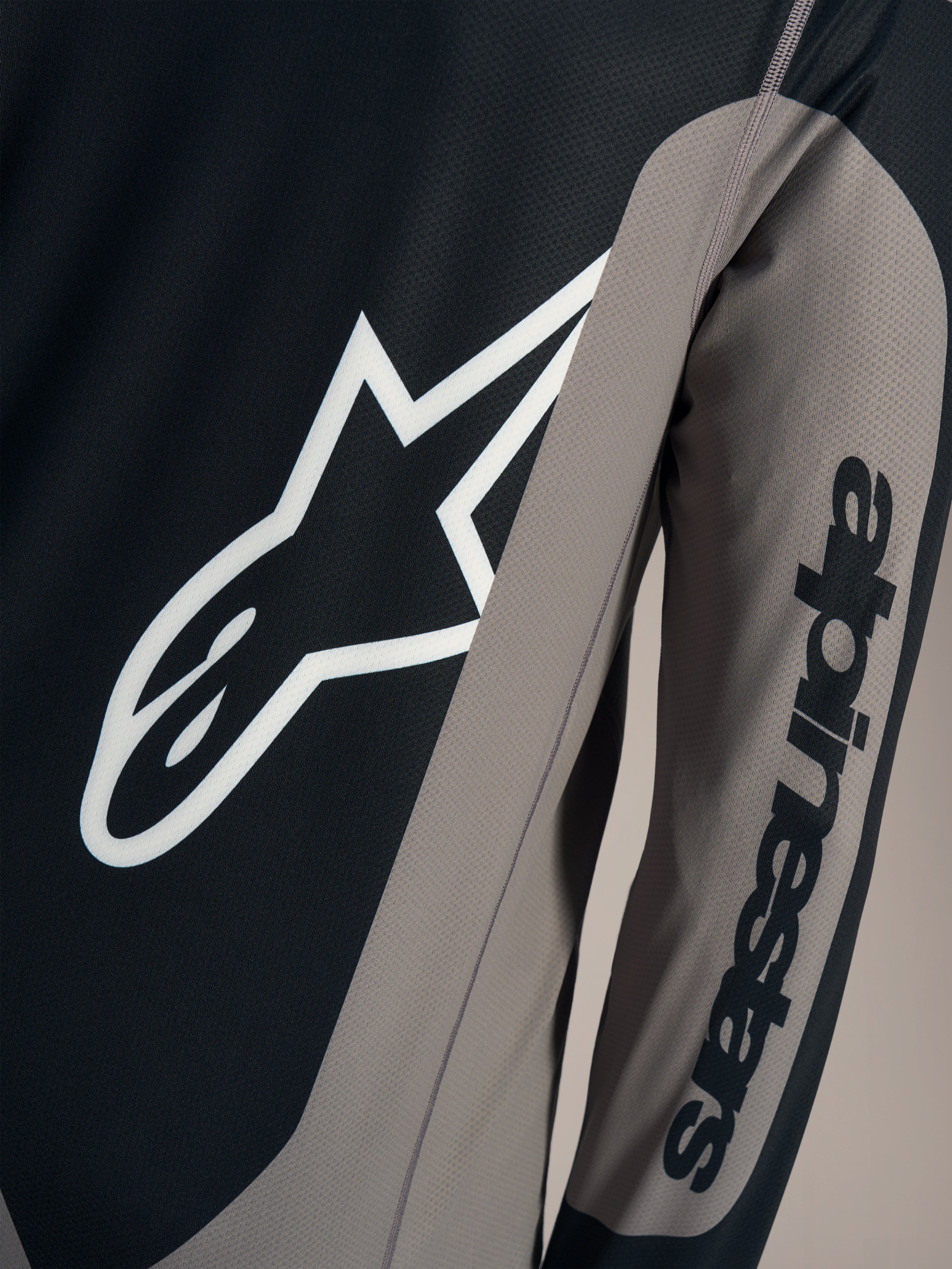 Grijze A-Dura Race jersey detail met wit Astars borstlogo en Alpinestars woordmerk op de mouw.