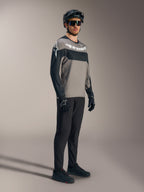 A-Dura Race Jersey met lange mouwen in grijs en zwart met witte logo's, gecombineerd met een mountainbikebroek en helm.