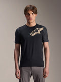 Mannelijk model draagt Alpinestars A-Dura Lipan jersey met korte mouwen, zwart MTB mountainbike-jersey met beige sterlogo en donkergrijze mouwen, gecombineerd met een grijze fietsbroek, casual sportkleding