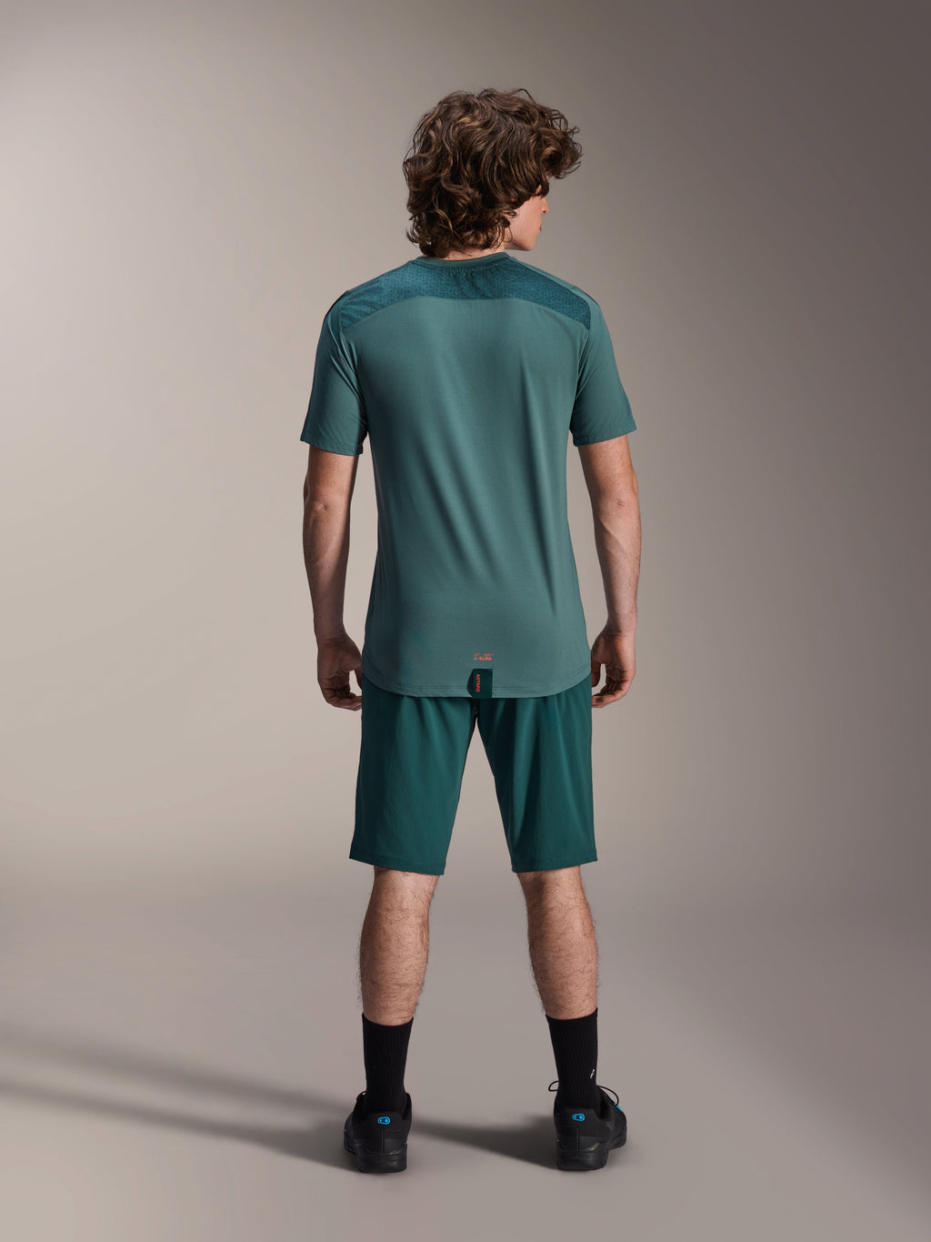Alpinestars A-Dura Lipan Jersey met korte mouwen in Silver Pine, achteraanzicht met de getextureerde jacquard schouderpanelen en verlengde achterkant, gedragen met bijpassende donkergroene mountainbike shorts en zwart schoeisel