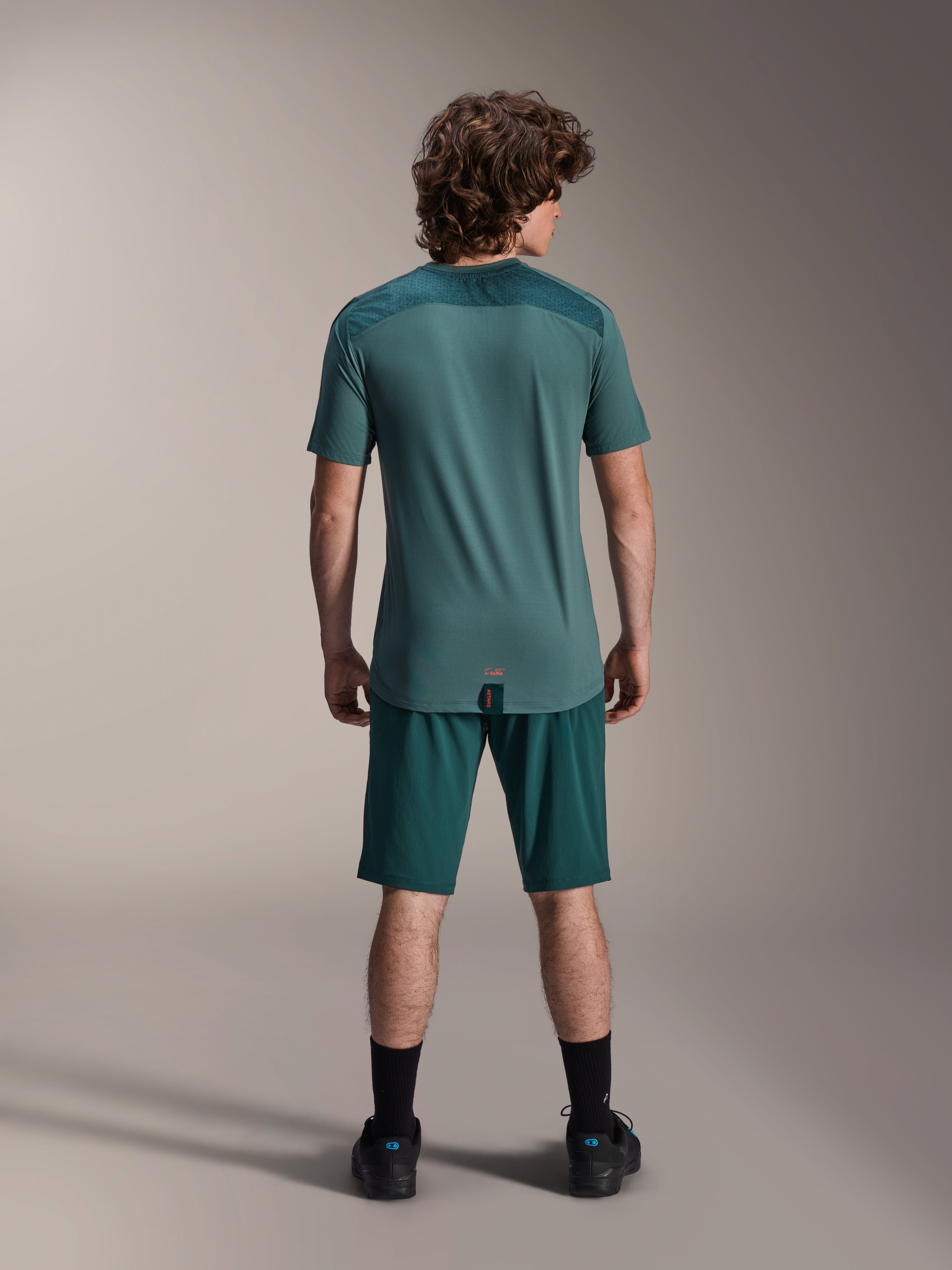 Alpinestars A-Dura Lipan Jersey met korte mouwen in Silver Pine, achteraanzicht met de getextureerde jacquard schouderpanelen en verlengde achterkant, gedragen met bijpassende donkergroene mountainbike shorts en zwart schoeisel