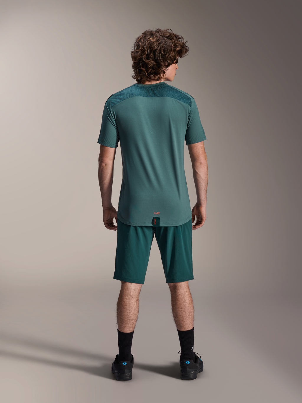 Alpinestars A-Dura Shorts en A-Dura Lipan SS Jersey, Dark Pine groen, achteraanzicht op een model, performance mountainbike-kleding bestaande uit een shirt met korte mouwen en bijpassende shorts, off-road fietsoutfit