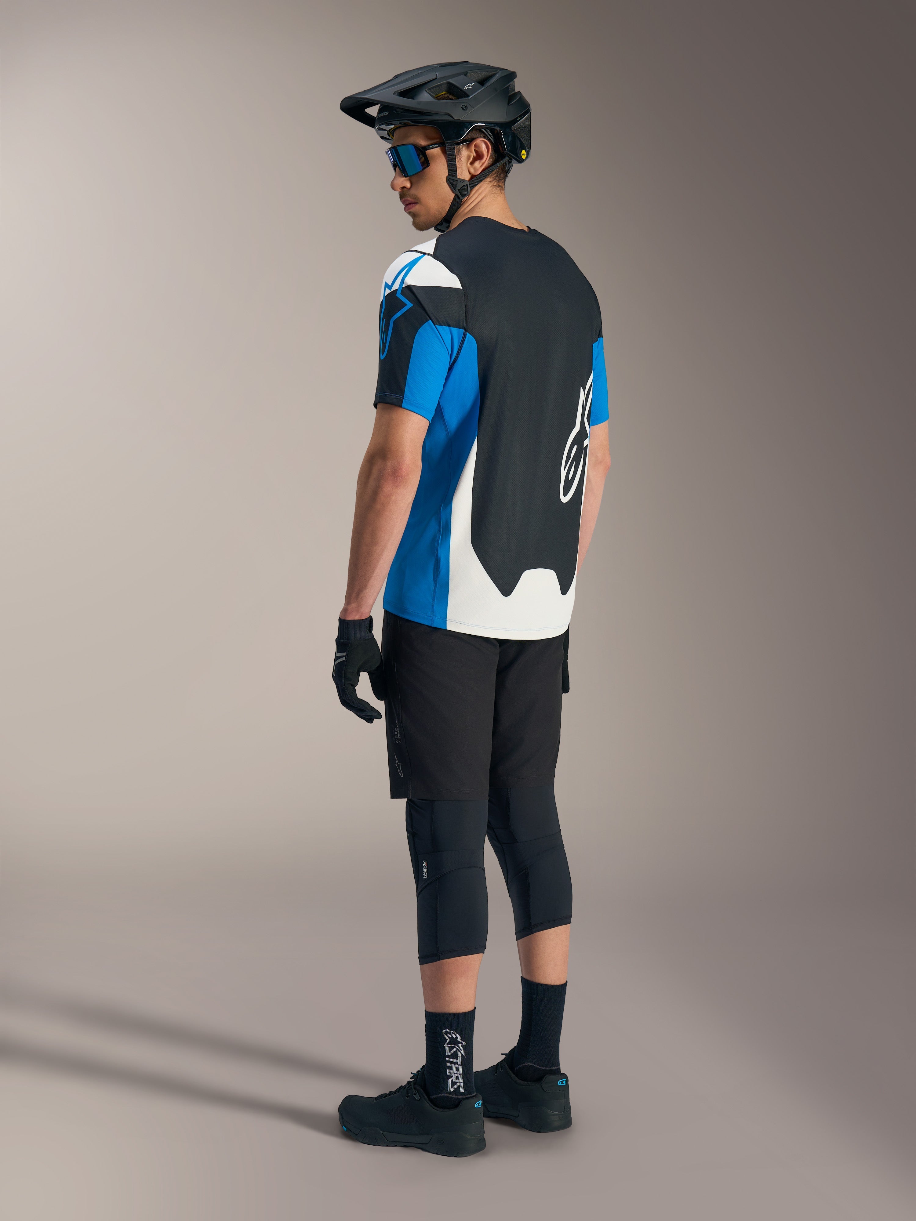 Alpinestars A-Dura Race SS jersey in blauw en zwart met zwarte MTB-shorts, helm en beschermende uitrusting.