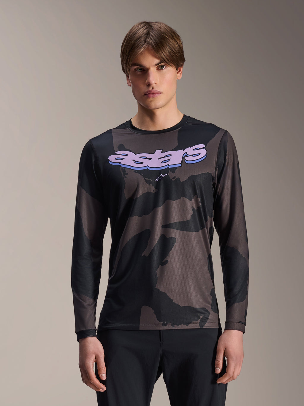 Alpinestars A-Dura Hollow Camo jersey met lange mouwen, MTB mountainbike-shirt, zwart en grijs camouflagepatroon, paarse 'astars' graphic op de borst, gedragen door model met zwarte broek, casual performance-ontwerp