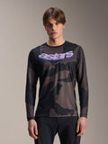 Alpinestars A-Dura Hollow Camo jersey met lange mouwen, MTB mountainbike-shirt, zwart en grijs camouflagepatroon, paarse 'astars' graphic op de borst, gedragen door model met zwarte broek, casual performance-ontwerp
