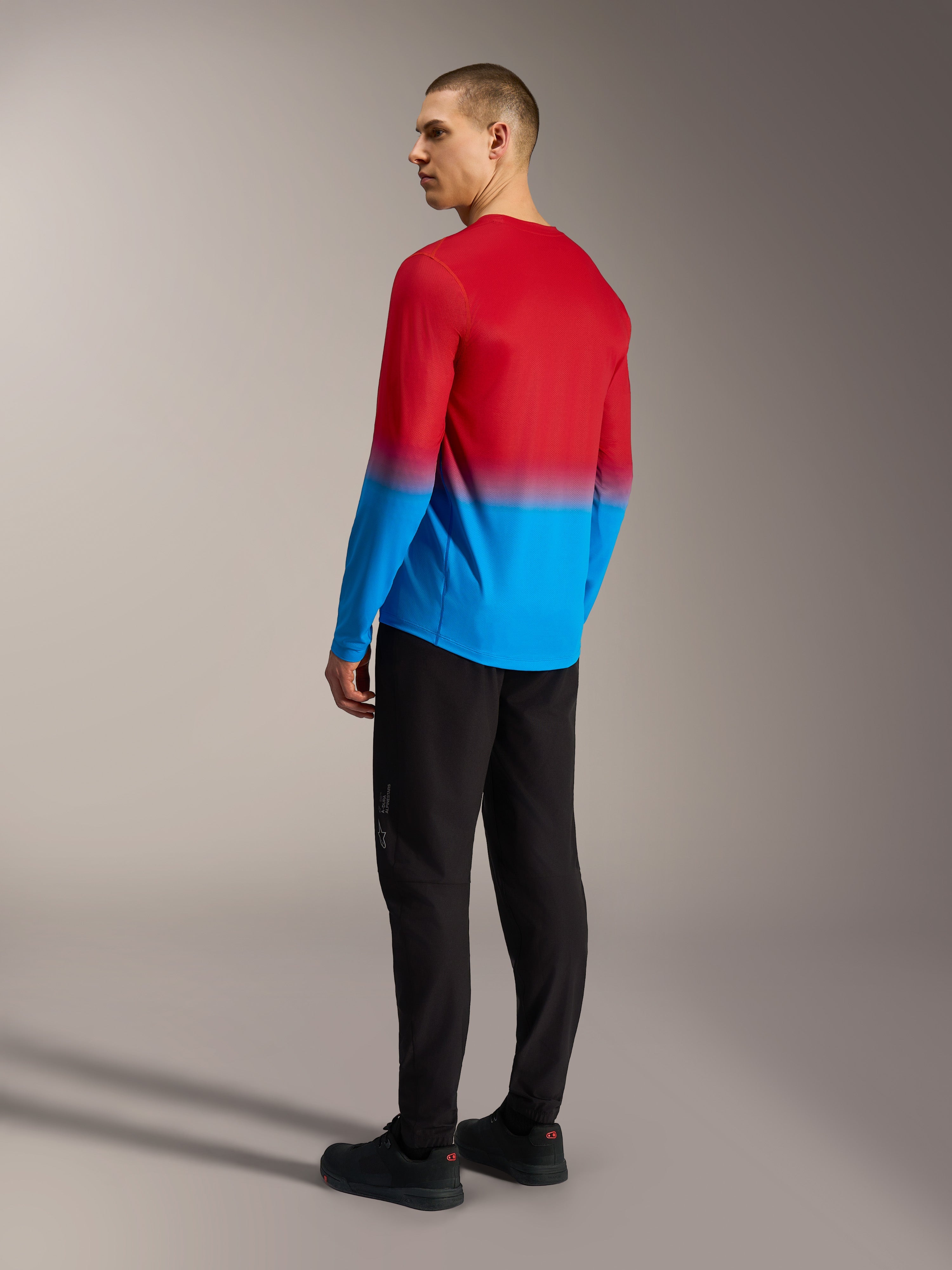 Alpinestars A-Dura ASTARS 2.0 MTB-jersey, rood-blauw kleurverloop, achteraanzicht op model in zwarte broek.