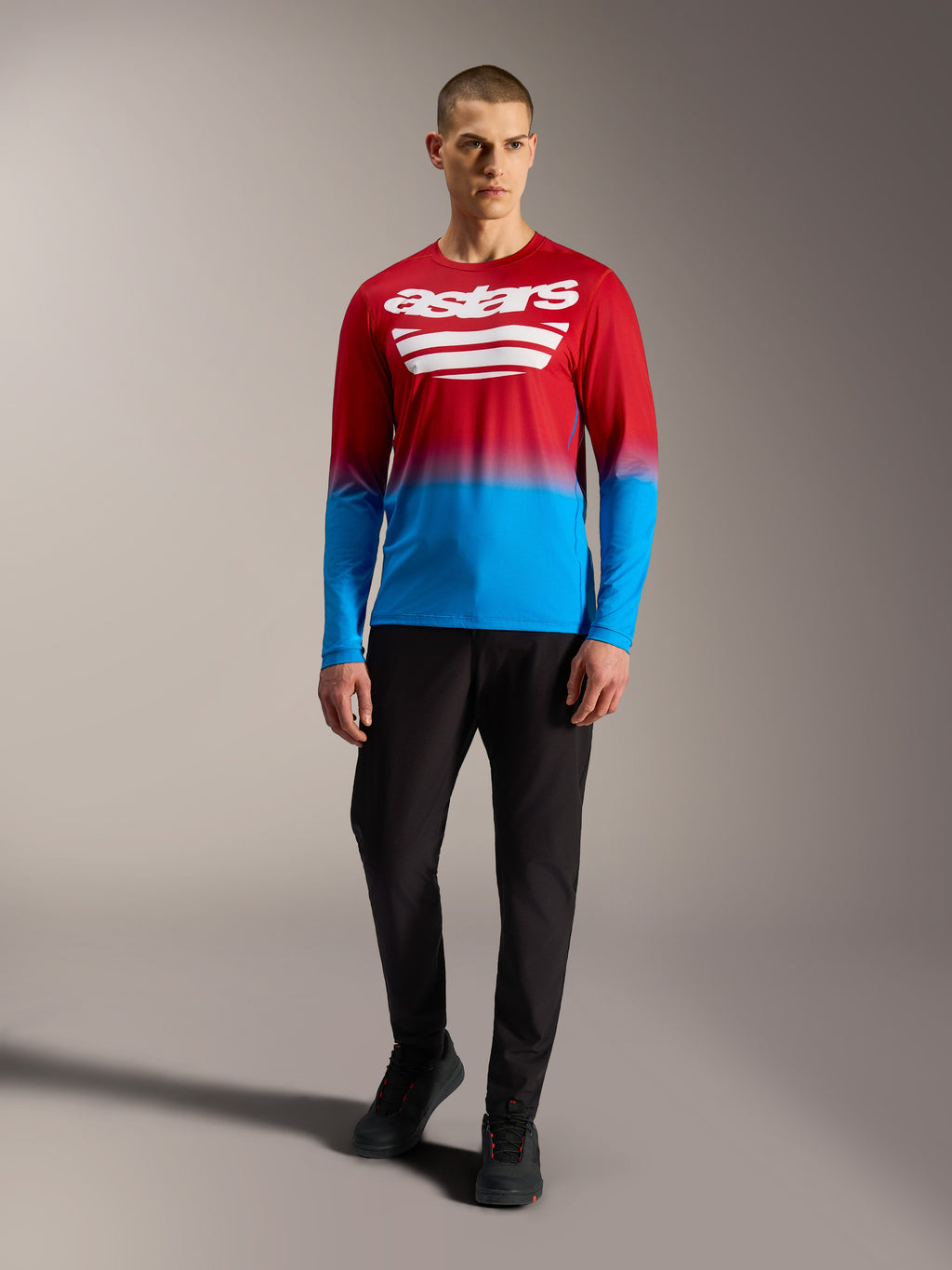A-Dura ASTARS 2.0 MTB-jersey met lange mouwen, rood-blauw kleurverloop en witte logo's, met een zwarte broek.