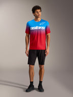 A-Dura ASTARS Jersey 2.0 met Bright Red Blue kleurverloop, wit logo, zwarte MTB-short en fietsschoenen.