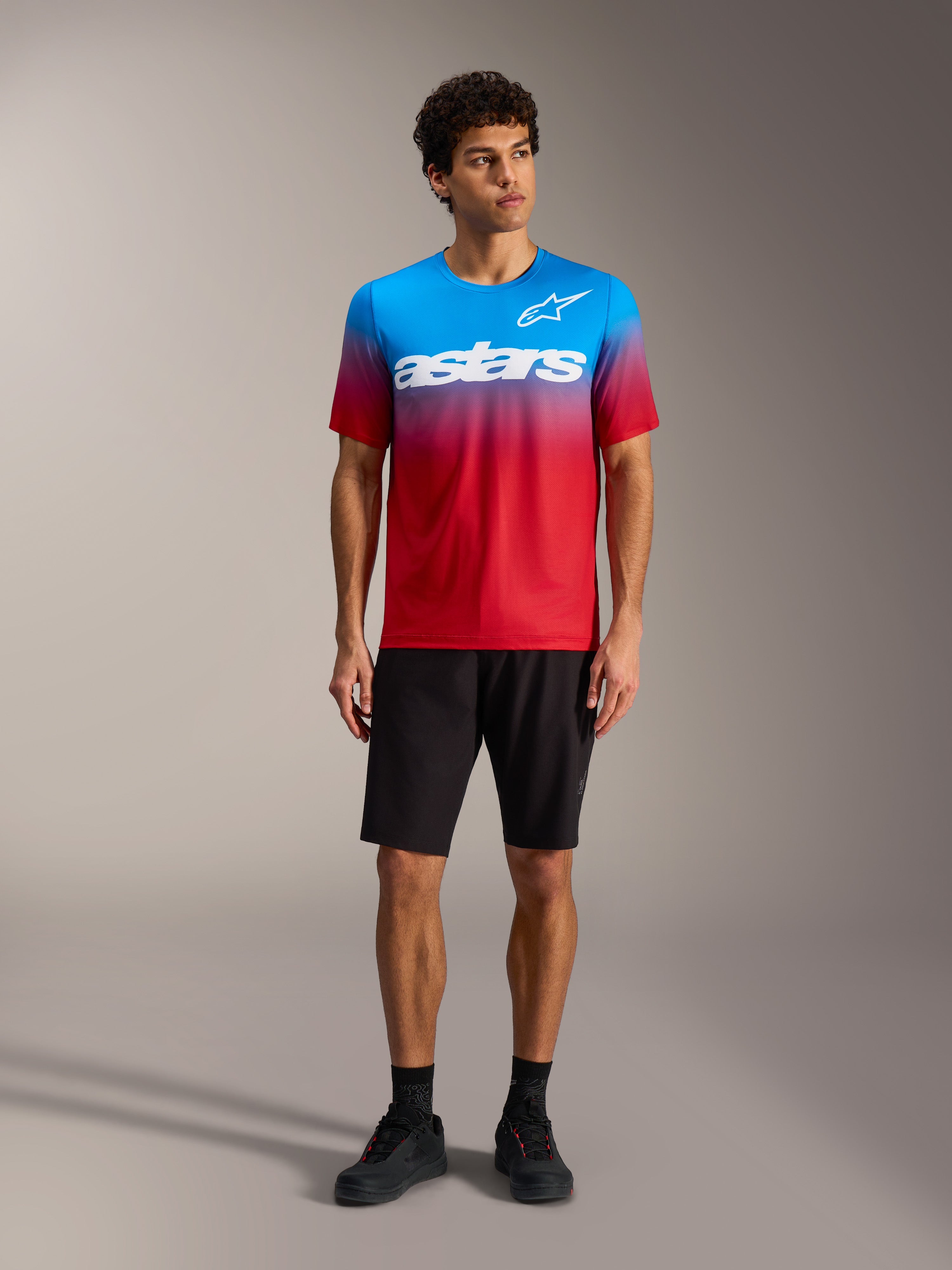 A-Dura ASTARS Jersey 2.0 met Bright Red Blue kleurverloop, wit logo, zwarte MTB-short en fietsschoenen.