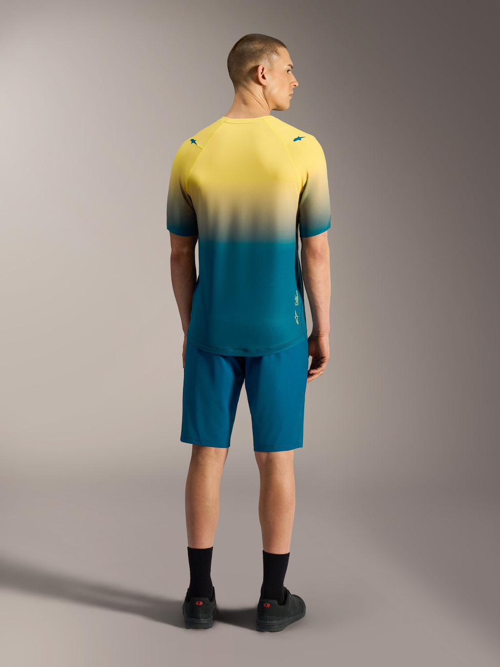 A-Dura ASTARS Jersey 2.0 met korte mouwen, geel en blauwgroen kleurverloop, achteraanzicht op model.