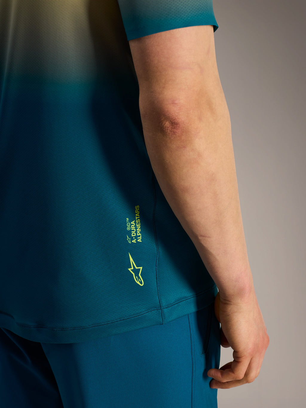 Alpinestars A-Dura ASTARS Jersey 2.0 detail in blauwgroen, met een fluogeel logo en branding aan de zijkant.