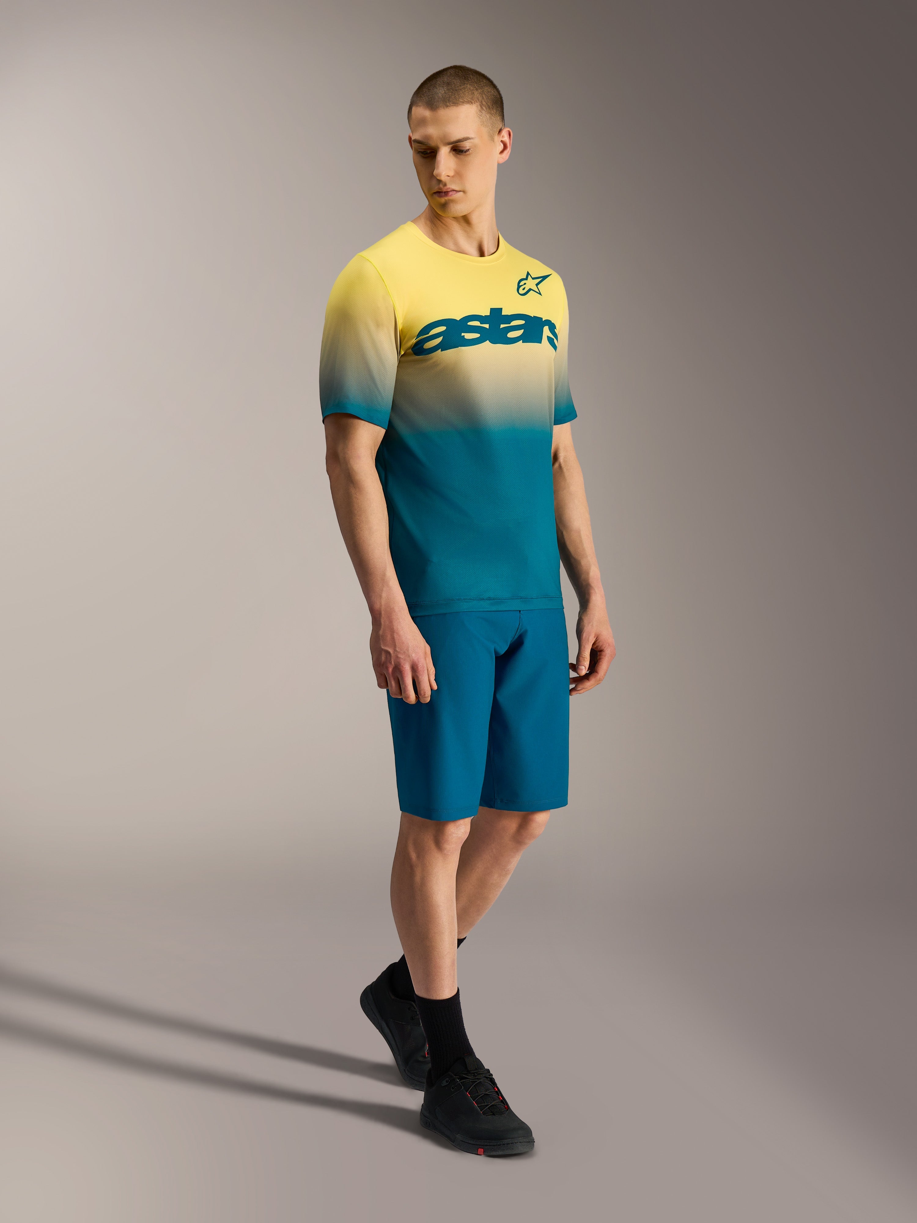 A-Dura ASTARS 2.0 MTB-jersey met geel-blauw kleurverloop en borstlogo, korte mouwen, gedragen door een model.