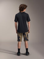 Alpinestars A-Dura Astar Jersey met korte mouwen, zwart, achteraanzicht op een model gecombineerd met MTB-shorts met camouflagepatroon en zwart schoeisel, casual technische mountainbikekleding