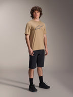 Mannelijk model in zwarte Alpinestars A-Dura Liner Shorts, gecombineerd met een beige A-Dura SS Jersey met grijs Astars-logo, zwarte fietssokken en mountainbikeschoenen, complete off-road fietsoutfit