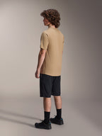Alpinestars A-Dura Liner Shorts in zwart en A-Dura SS Jersey in tan, gedragen door een mannelijk model in zijaanzicht, gecombineerd met zwarte sokken en fietsschoenen, mountainbike lifestyle kleding.