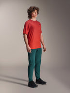 Model draagt Alpinestars A-Dura Pants in Dark Pine, gecombineerd met een rood A-Dura Rise Jersey met korte mouwen en zwarte MTB-schoenen, sportieve mountainbike-kleding in een studio-omgeving