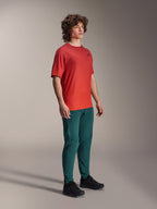 Alpinestars A-Dura Rise Jersey, korte mouwen, Spicy Orange, met een klein zwart logo op de borst, gedragen met een donker teal broek en zwarte schoenen, lichtgewicht vochtafvoerende mountainbikekleding