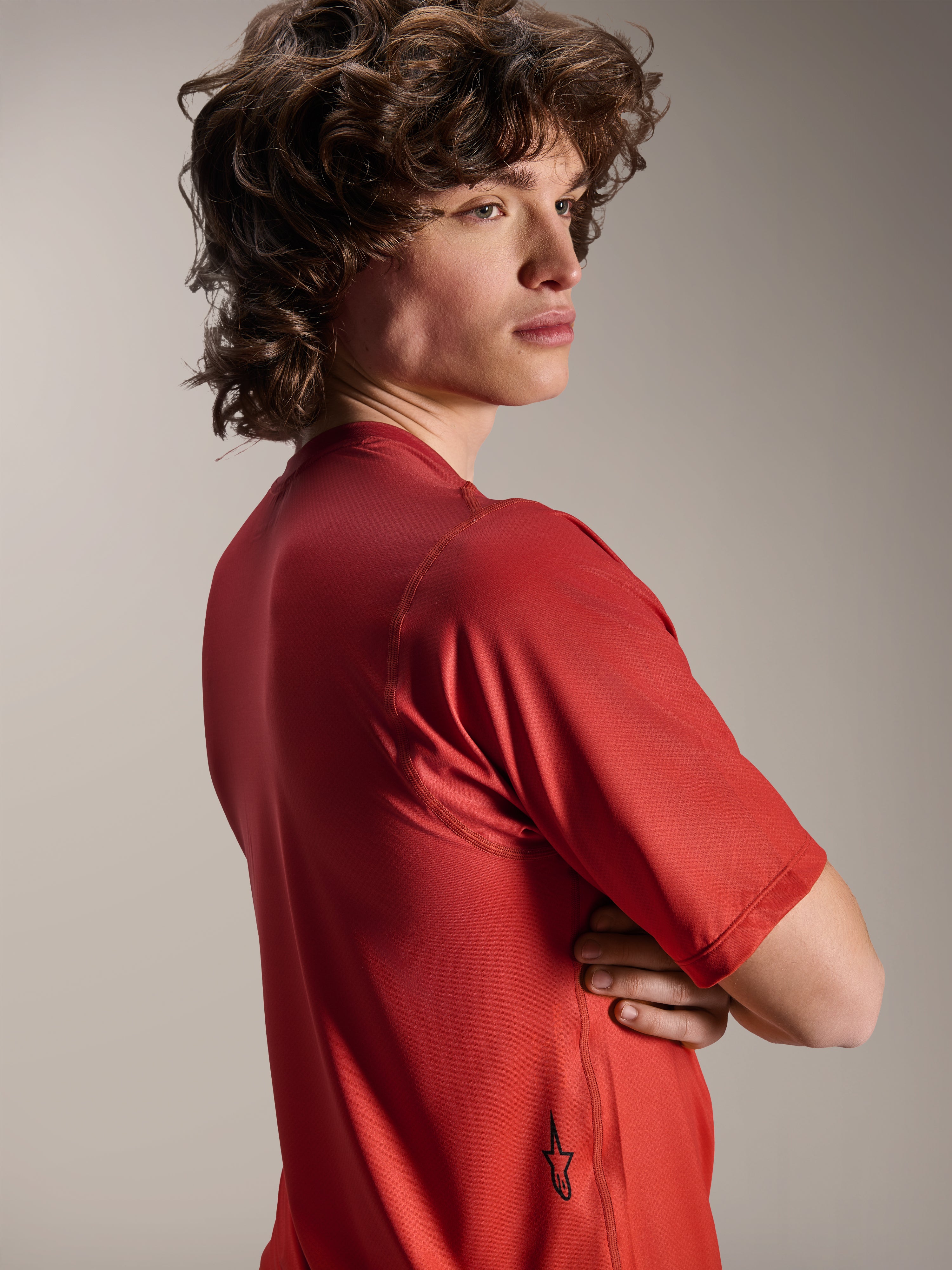 Alpinestars A-Dura Rise Jersey - korte mouwen, Spicy Orange, modelaanzicht vanaf de zij- en achterkant, toont een klein zwart Astars-logo op de onderste zoom, lichtgewicht getextureerde jacquardstof voor MTB-prestaties