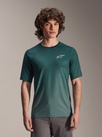 Alpinestars A-Dura Rise Jersey met korte mouwen, Silver Pine donkergroen, gedragen door een model, wit Astars-logo op de borst, lichtgewicht jacquard vochtafvoerende stof, casual mountainbike performance shirt