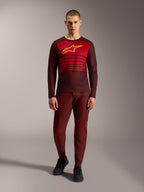 Alpinestars A-Dura Elite 2.0 MTB-trui in bordeauxrood met lange mouwen, geel borstlogo en rode strepen op de borst.