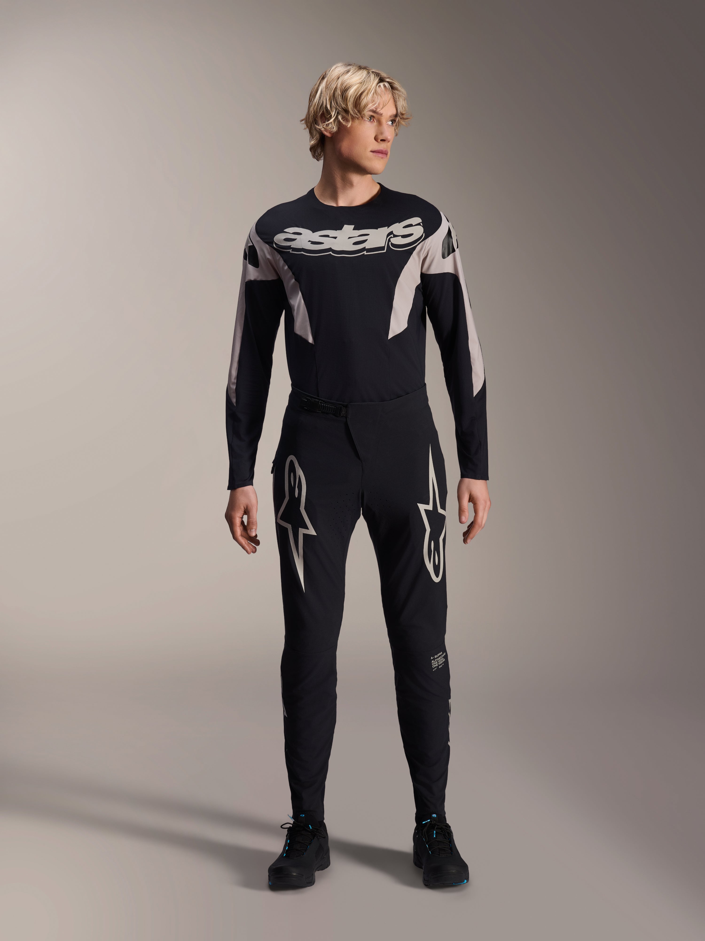 Alpinestars A-Supra Melt Jersey, MTB-jersey met lange mouwen, zwart met witte Astars-branding op de borst, gedragen met bijpassende zwarte mountainbikebroek met sterlogo's, strakke performance fietskleding
