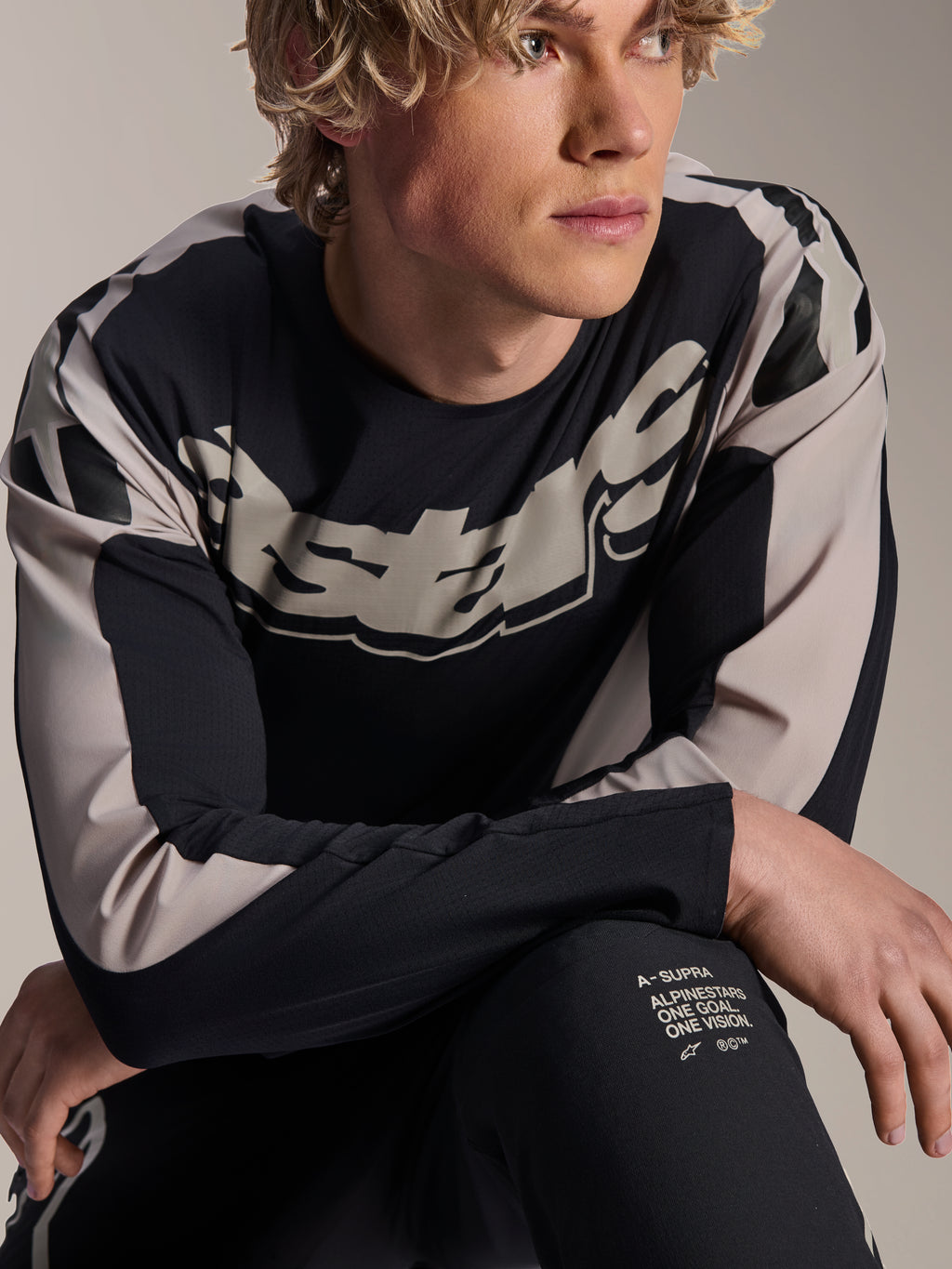 Alpinestars A-Supra Melt Jersey, MTB-shirt met lange mouwen, zwart met lichtgrijze graphics, gedragen door model, met opvallend logo op de borst en 'One Goal. One Vision.' branding, performance mountainbikekleding