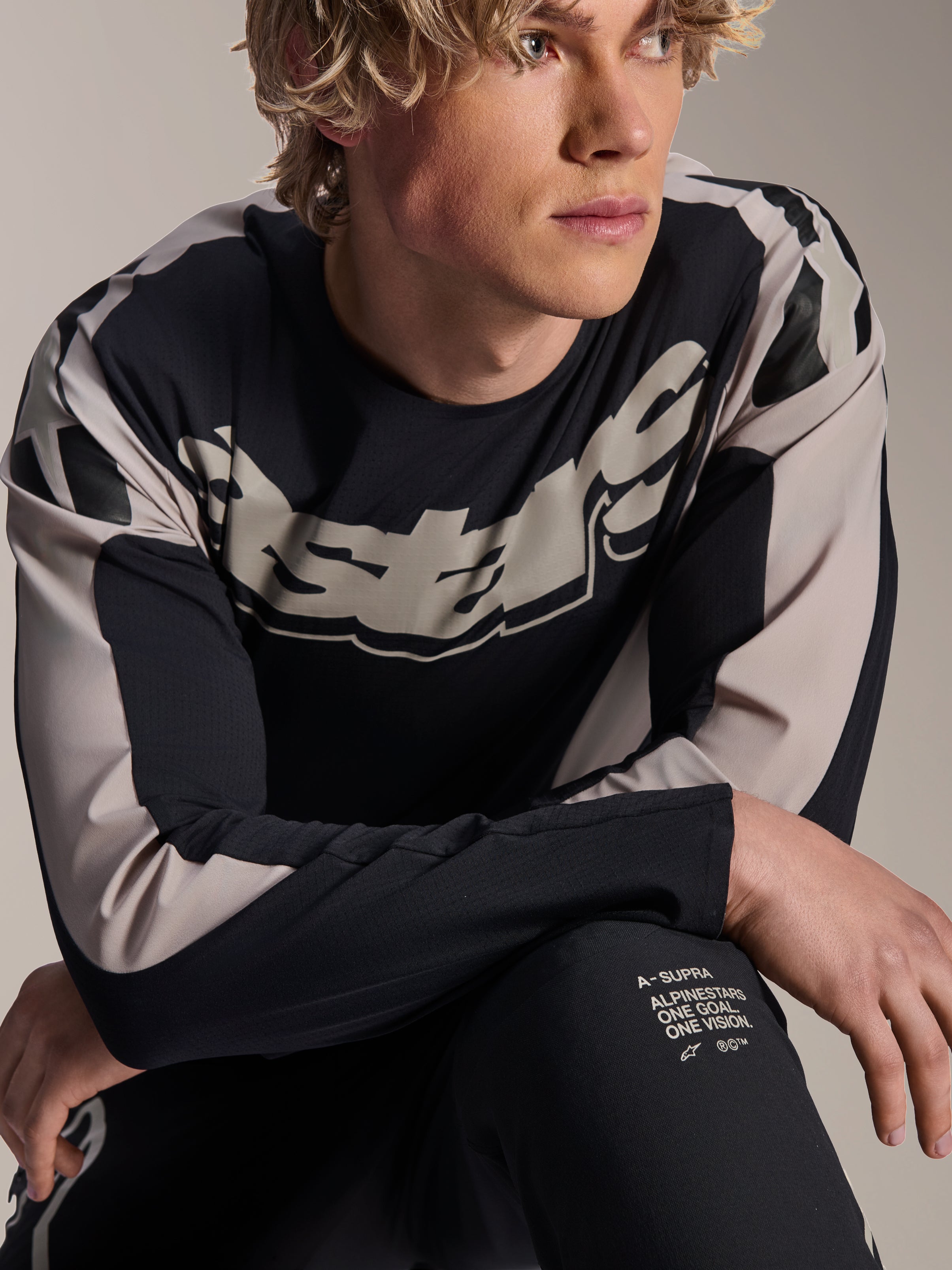 Alpinestars A-Supra Melt Jersey, MTB-shirt met lange mouwen, zwart met lichtgrijze graphics, gedragen door model, met opvallend logo op de borst en 'One Goal. One Vision.' branding, performance mountainbikekleding