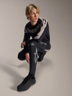 Alpinestars A-Supra Melt broek en jersey met lange mouwen, zwart en grijs, voorzien van opvallende witte branding en sterlogo's, gedragen door een mannelijk model in een gehurkte houding, gecoördineerde MTB-race-uitrusting
