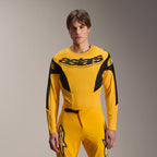 Alpinestars Limited Edition A-Supra Melt Gold uitrustingsset, geel MTB-fietsshirt met lange mouwen en bijpassende broek, zwarte Astars-branding op de borst, sportieve performance-pasvorm voor mountainbiken, model draagt de volledige uitrusting